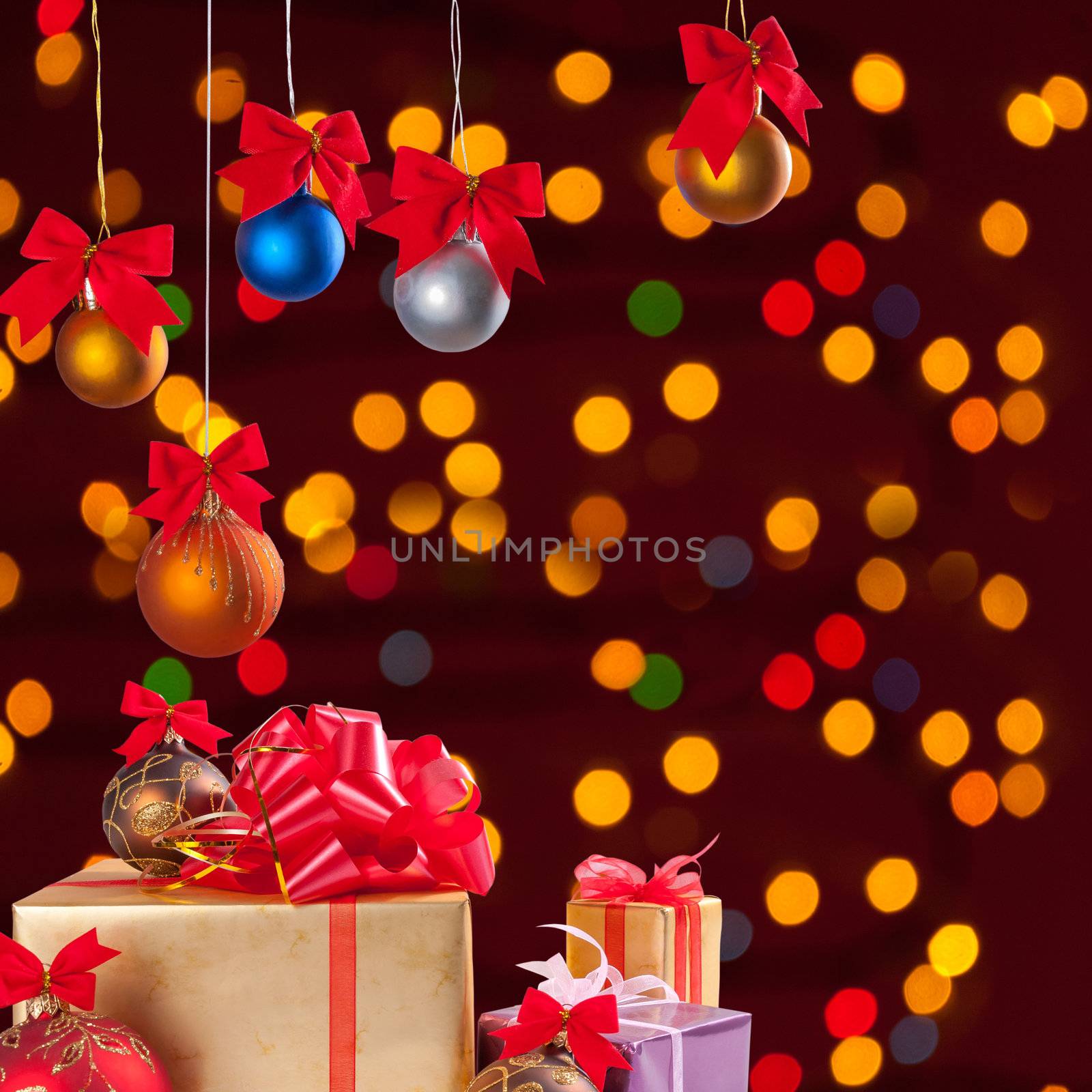 Christmas balls on ribbon and gifts on festive background