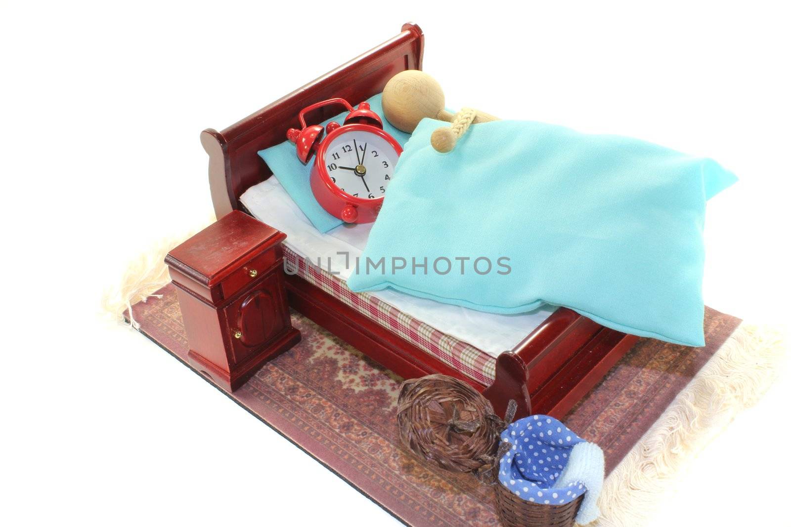 Sleep - a wooden doll and alarm clock in bed with bedside table and blue bedding
