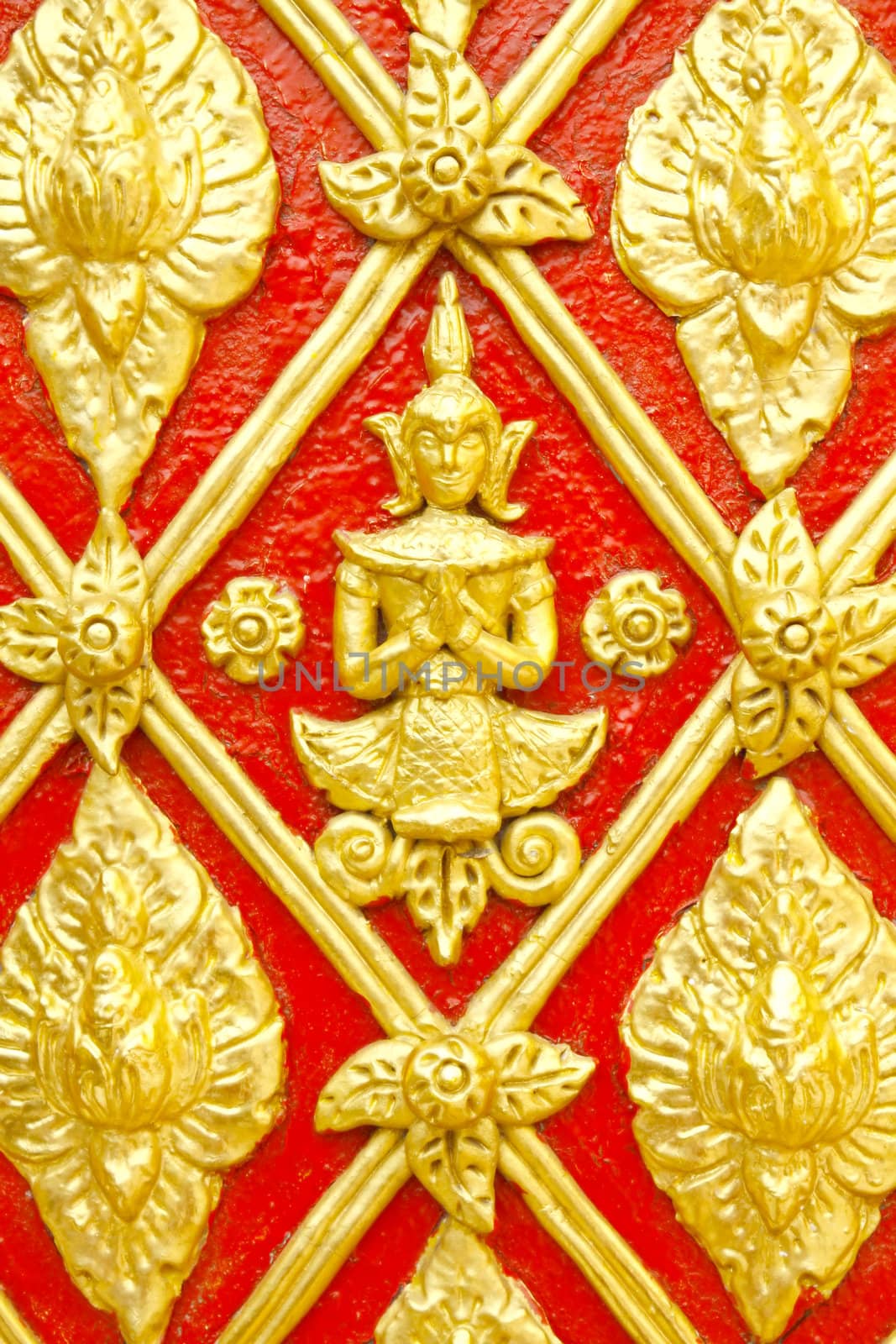 Stucco Thai pattern on wall are decorated with gold color on red background.