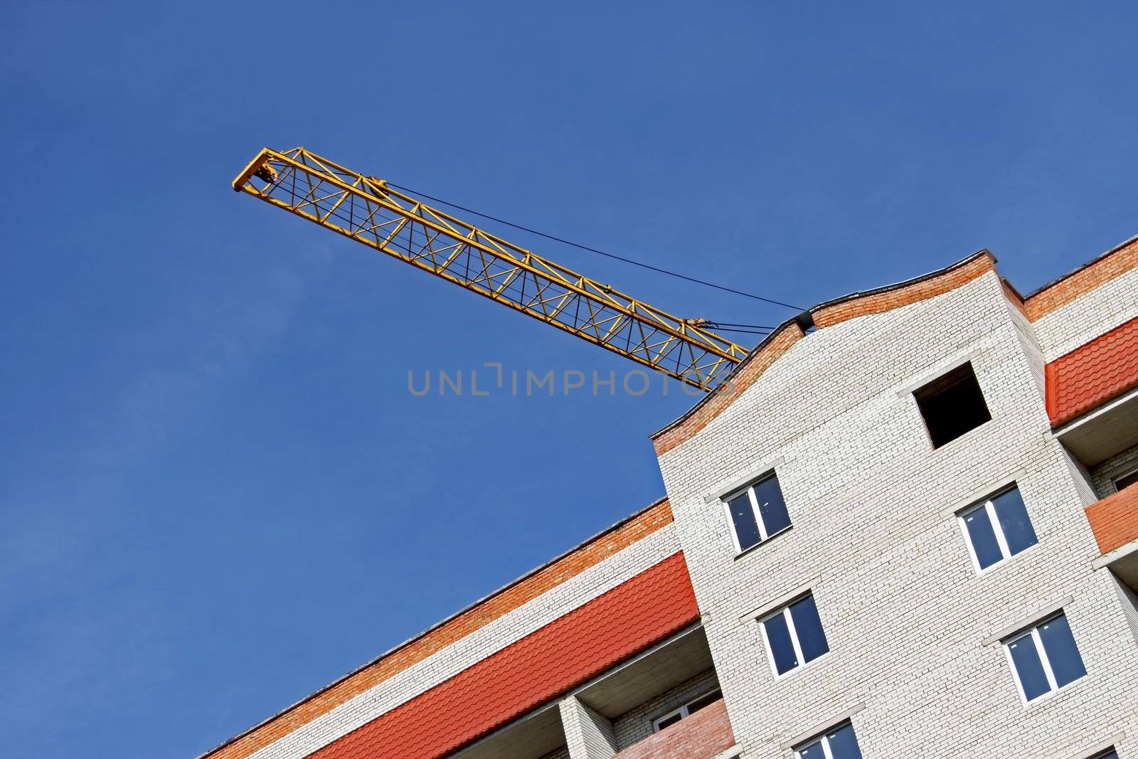 Building crane boom over construction against a blue sky