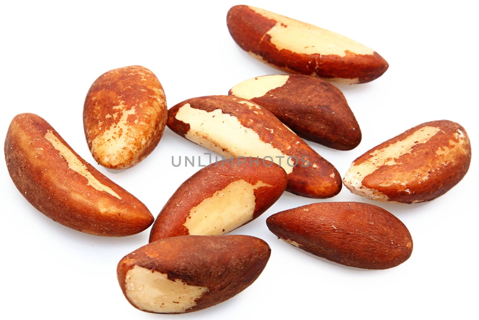 Nine fresh brazil nuts raw over white.