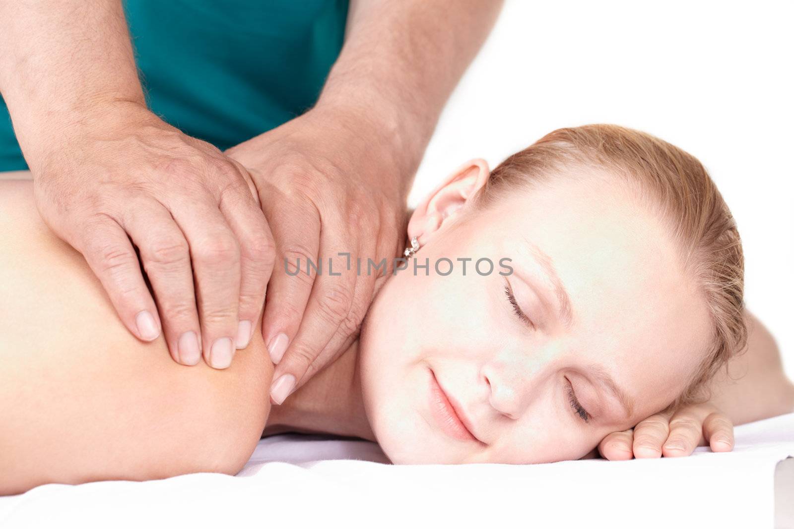 A young pretty girl of 25 on a seance of medical (health) massage in a light study. Her eyes are closed, a light smile on her face.