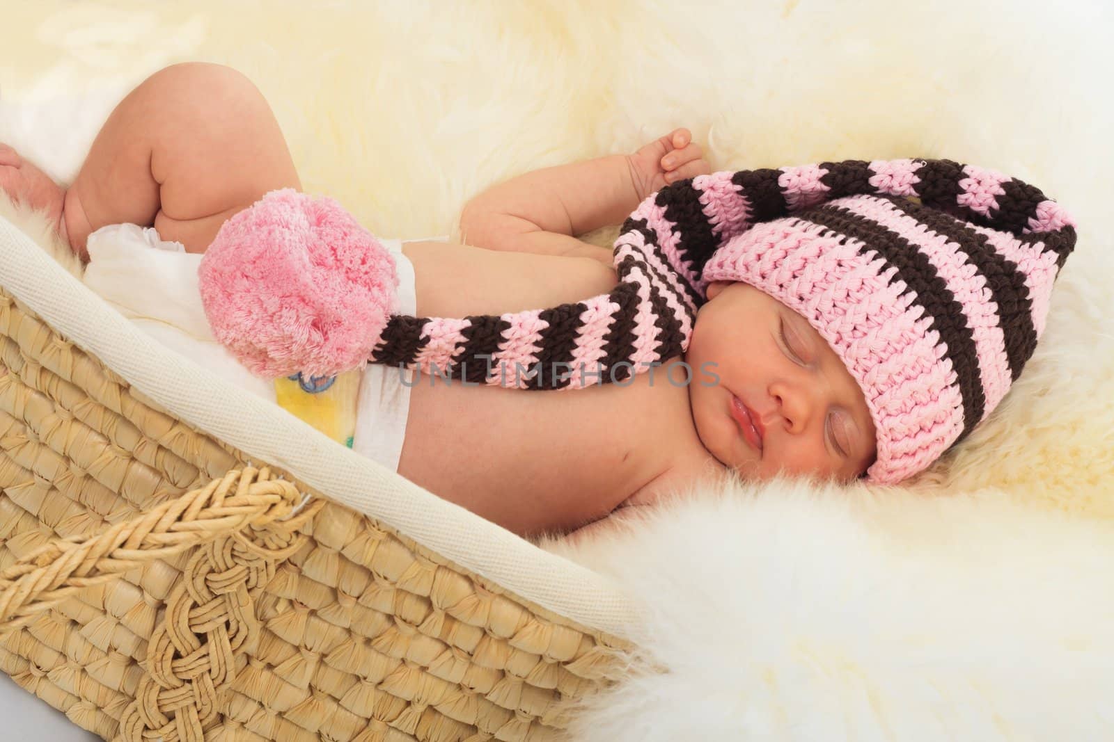 infant sleeping on a white sheepskin in a wicker basket.