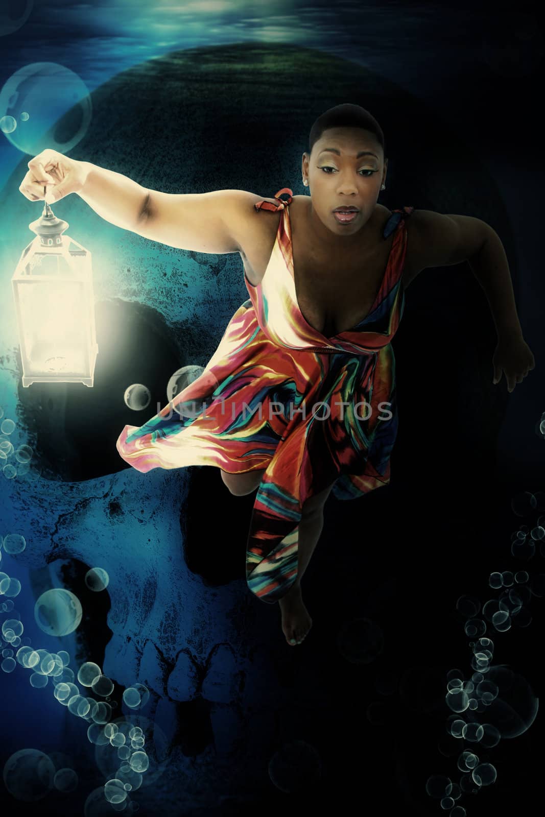 Beautiful Black Woman Swimming Underwater with Lantern. Human skull in background.
