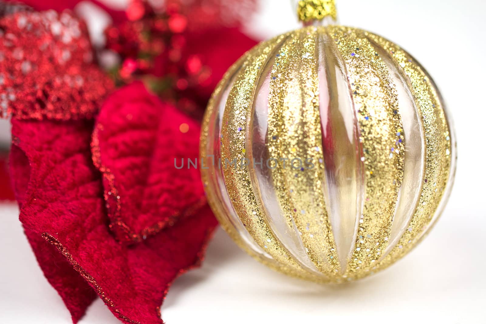 A vibrant red poinsettia with a gold decorated glass bauble