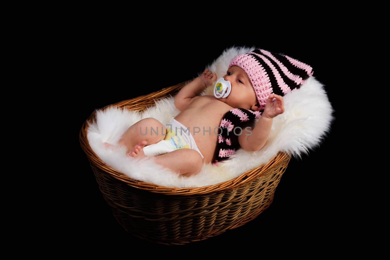 Newborn Child in a wicker basket on a black background.