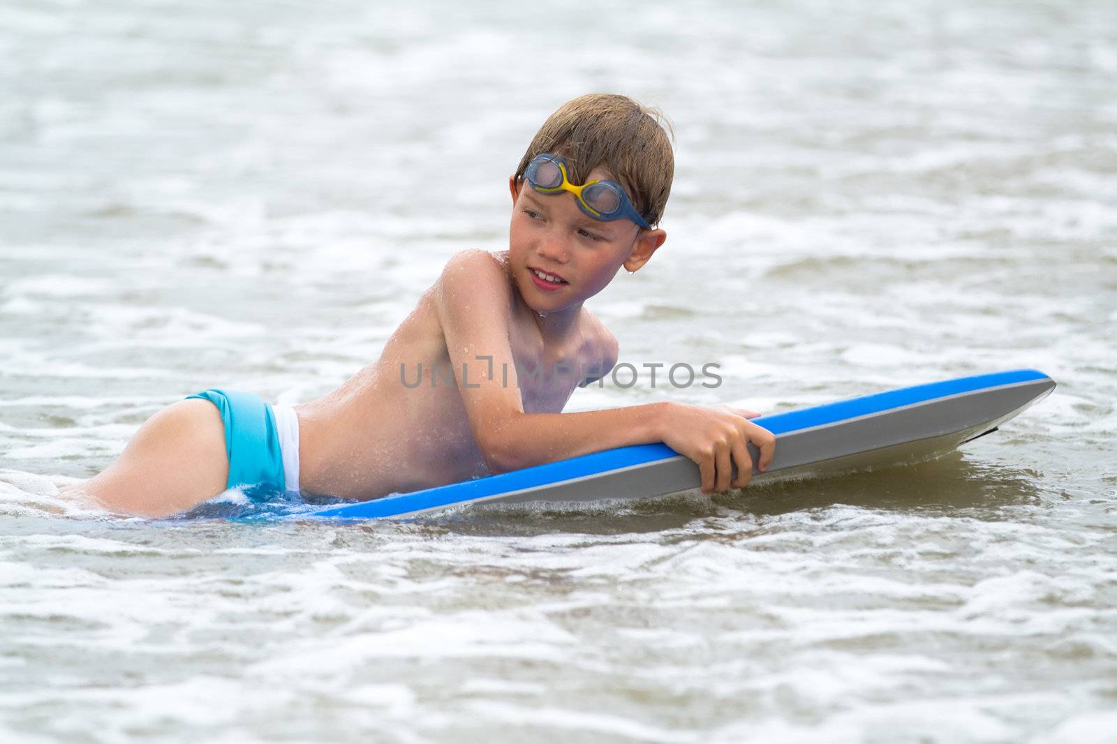 Young child with a bodyboard on the beach by chrisroll