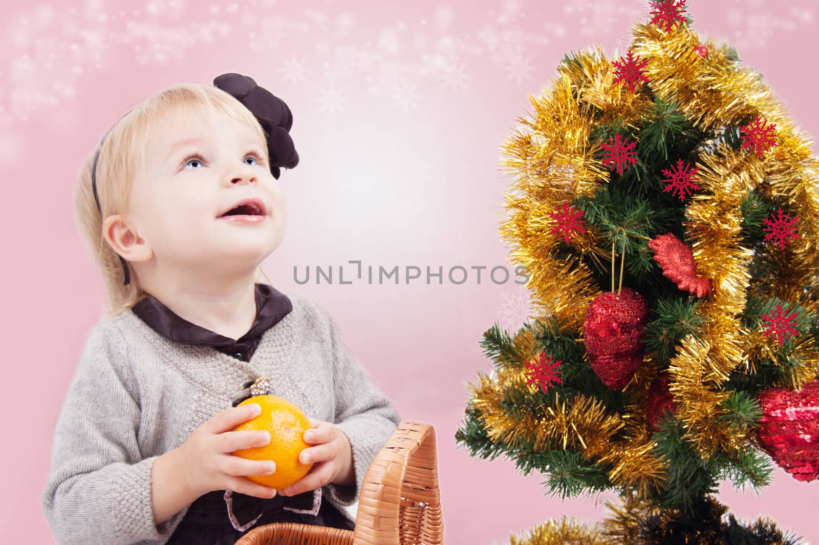 Surprised little girl looking up under Christmas tree