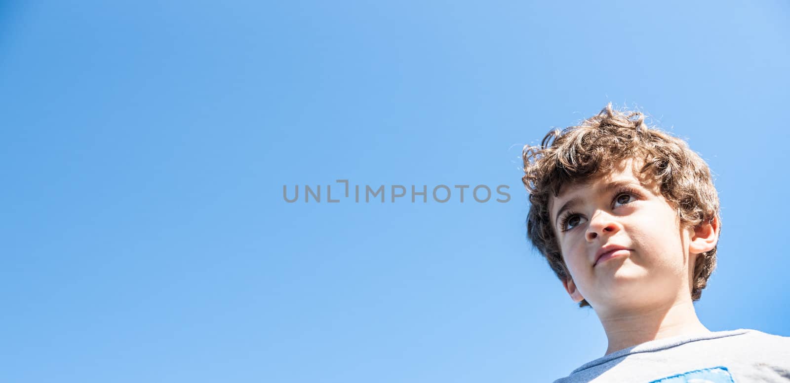 Young boy, isolated against blue sky. by brians101