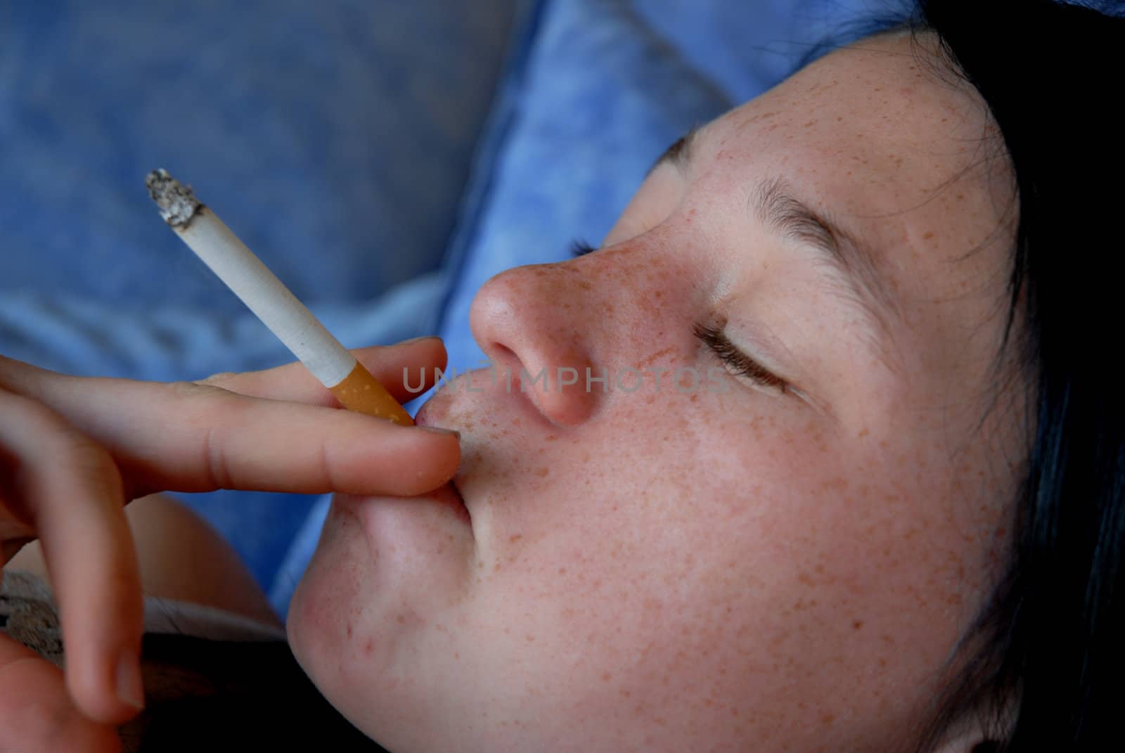 a young teenager smoking a cigarette laid down