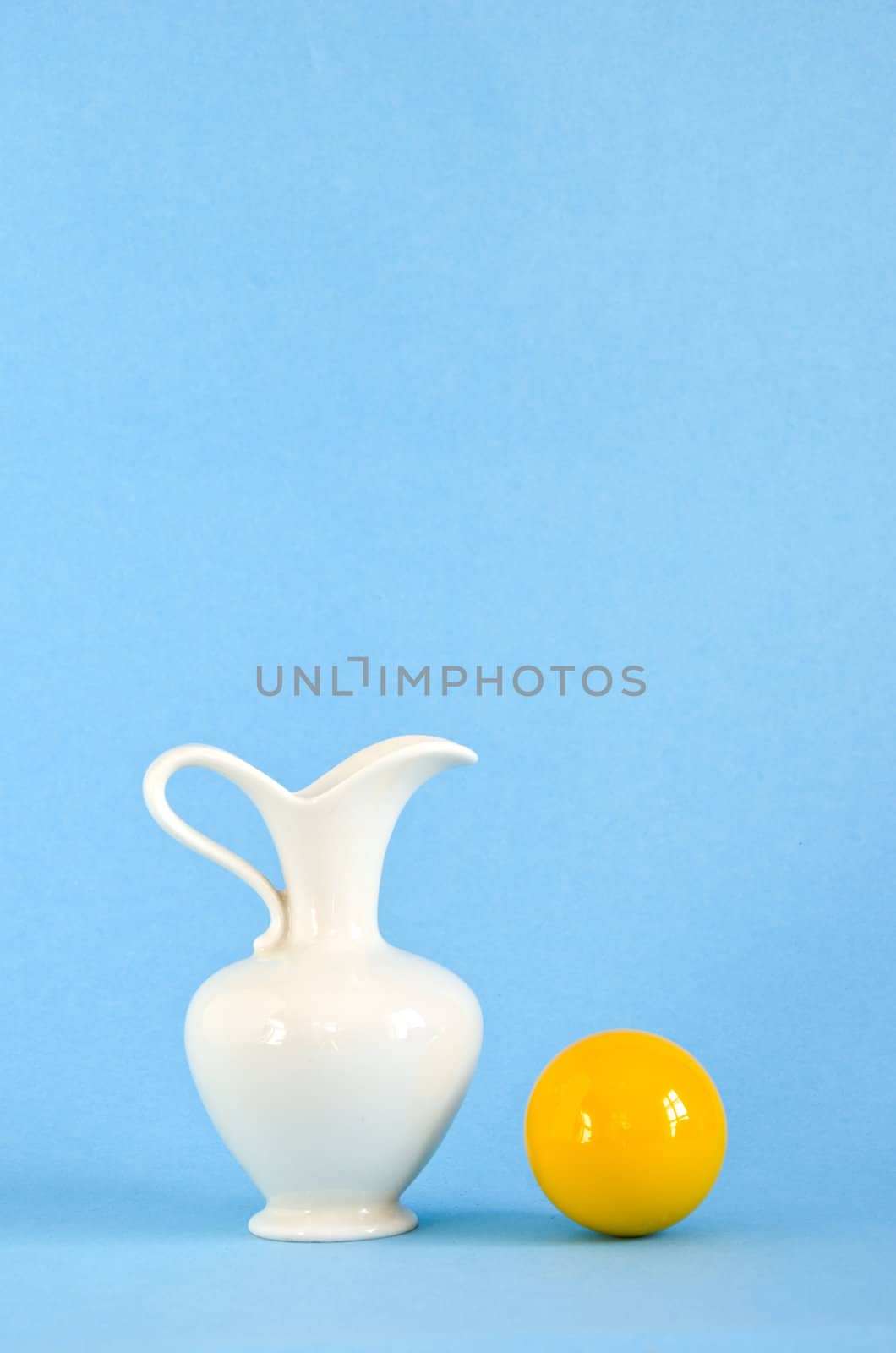 white vase and yellow ball on azure background