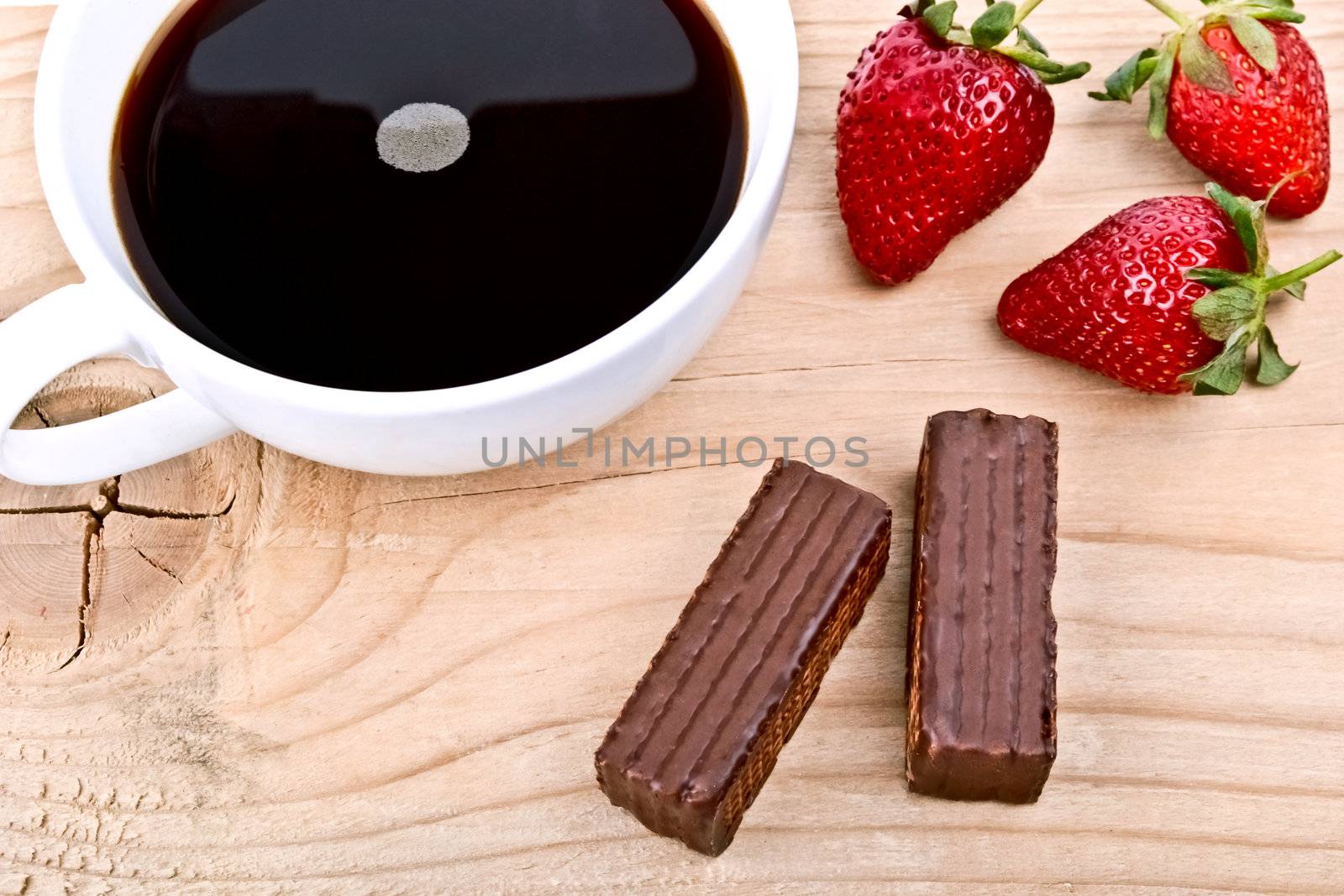 Strawberry with a cup of coffee and chocolate on wood