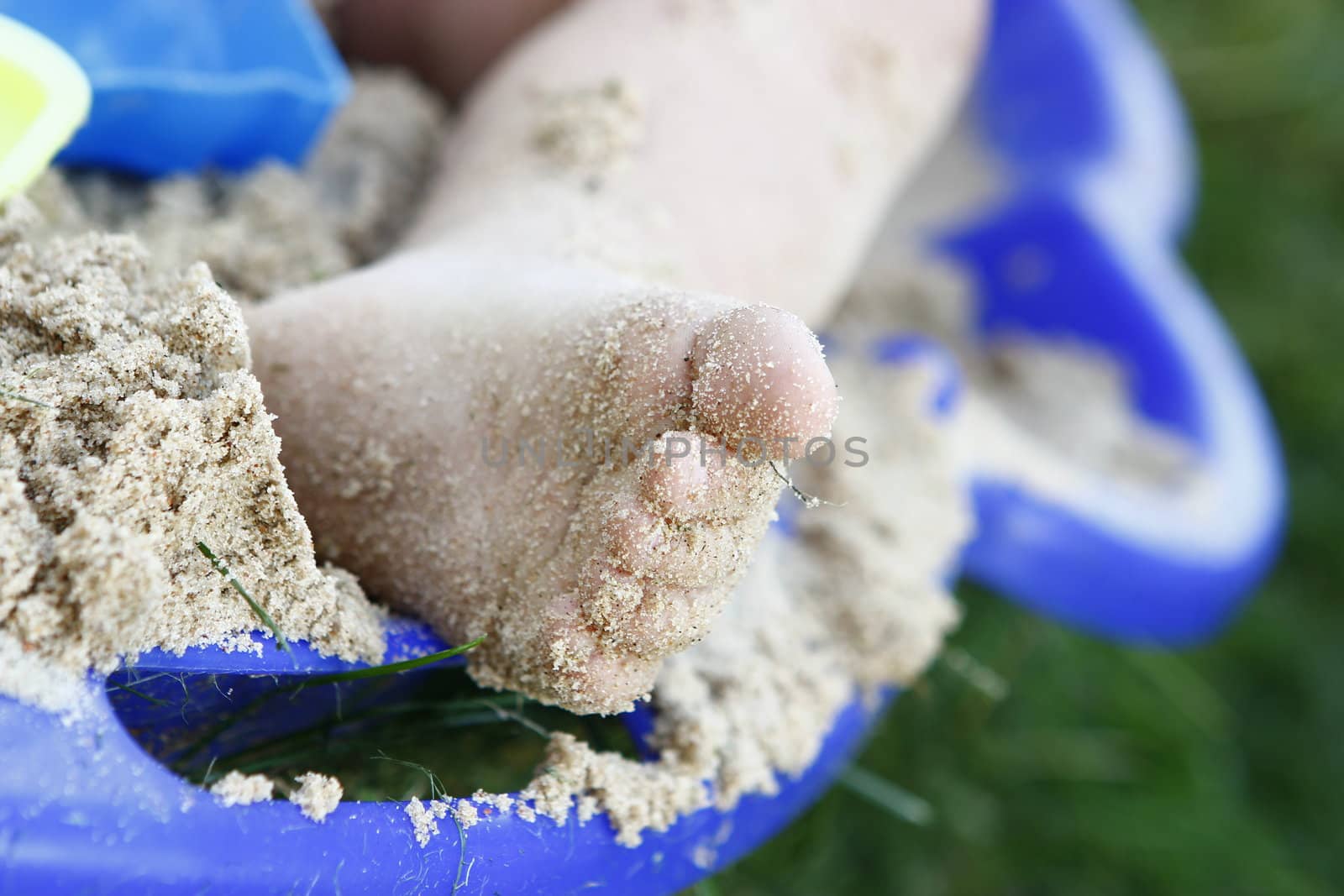 child`s leg caved with sand in the sandbox