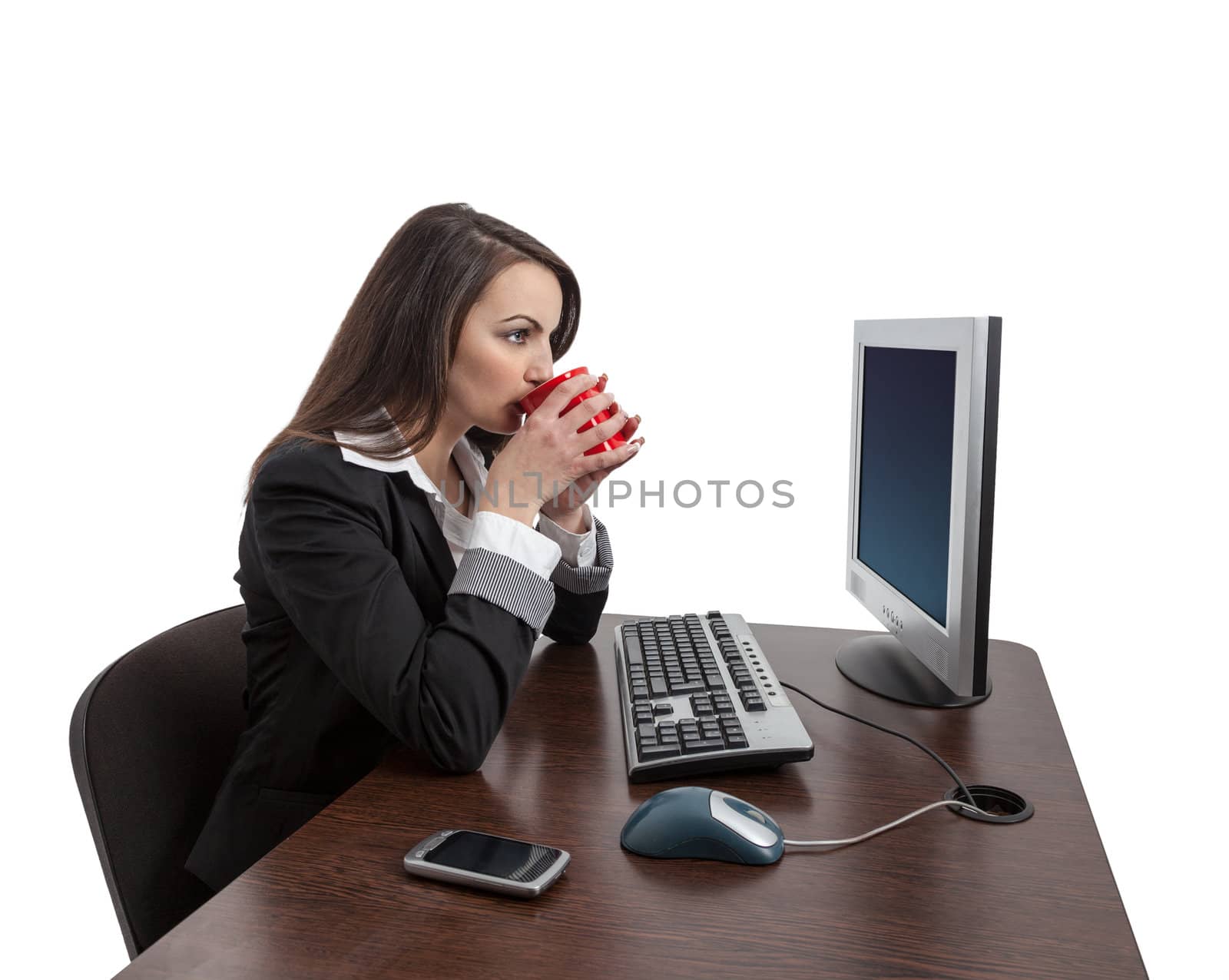 Young businesswoman drinking a cup of coffee at her desk in the office, isolated against a white background.