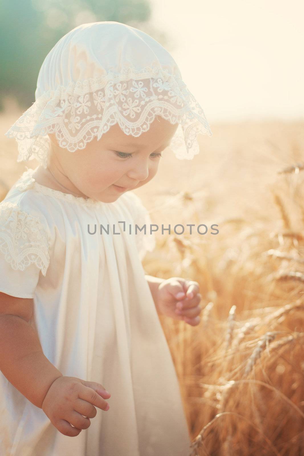 Laughing kid in sunny wheat  field in vintage dress