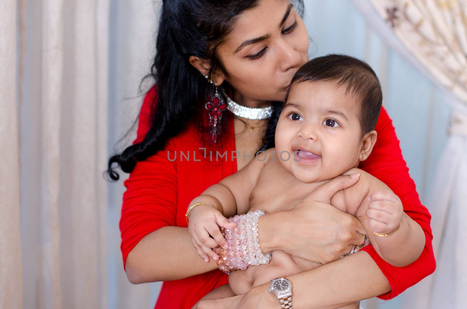 Indian mother kissing her baby girl, indoor