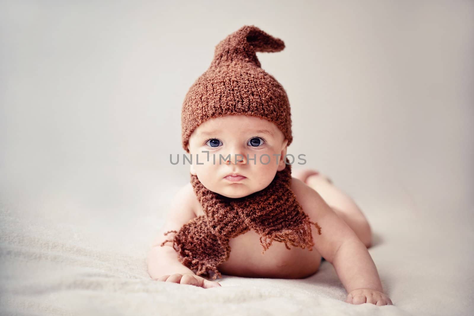 newborn baby in cap and scarf looking into the camera
