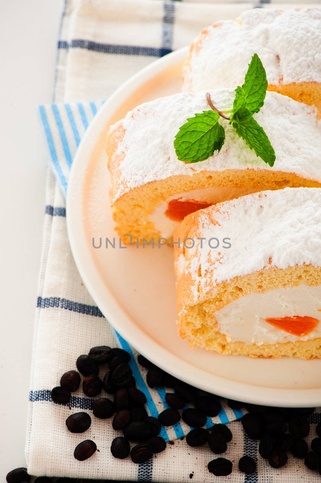 Sponge roll cake with orange cream and fresh mandarin. Fresh ,mMint and icing sugar as decoration on the top.