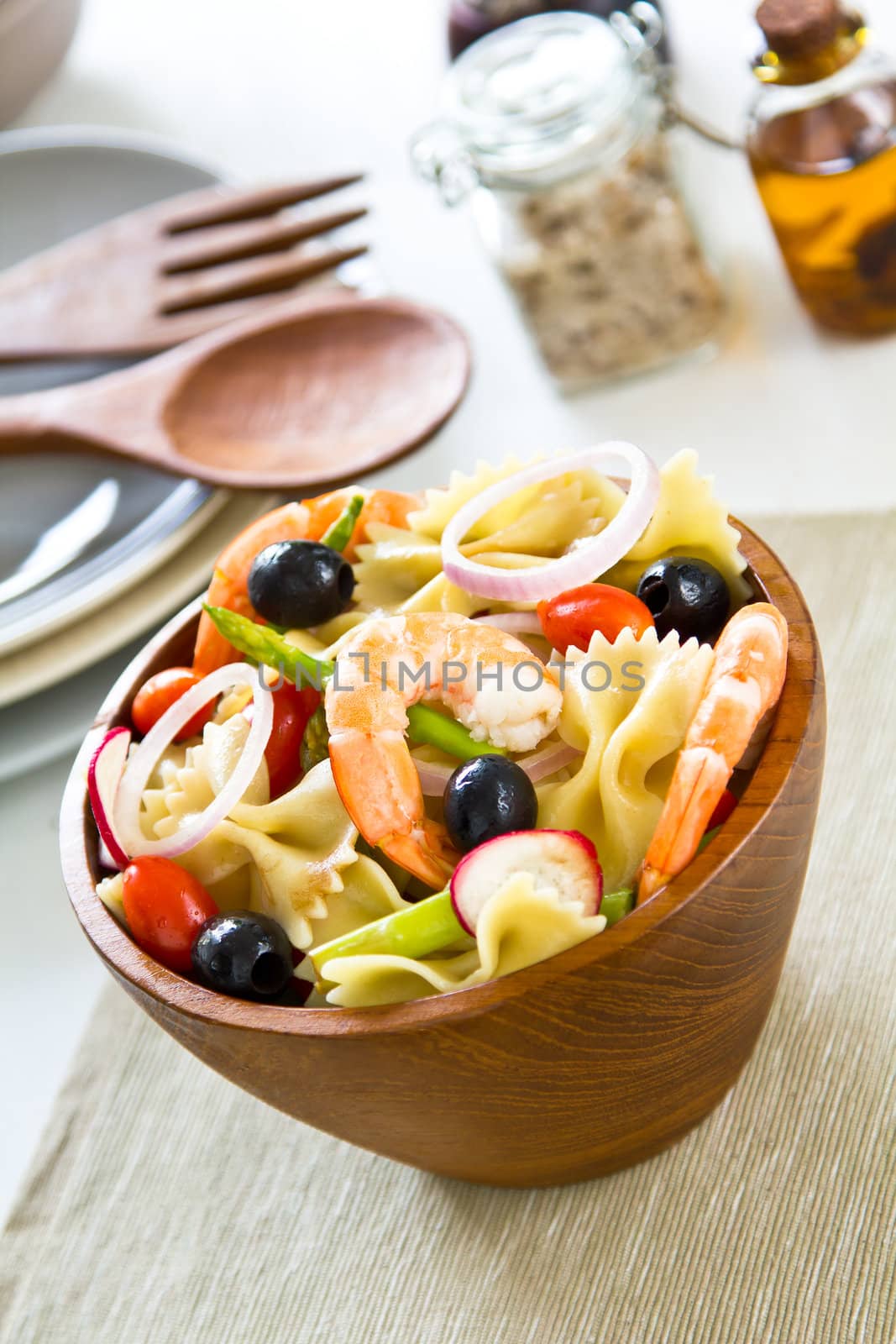 Farfalle with prawn and olive  salad in wood bowl