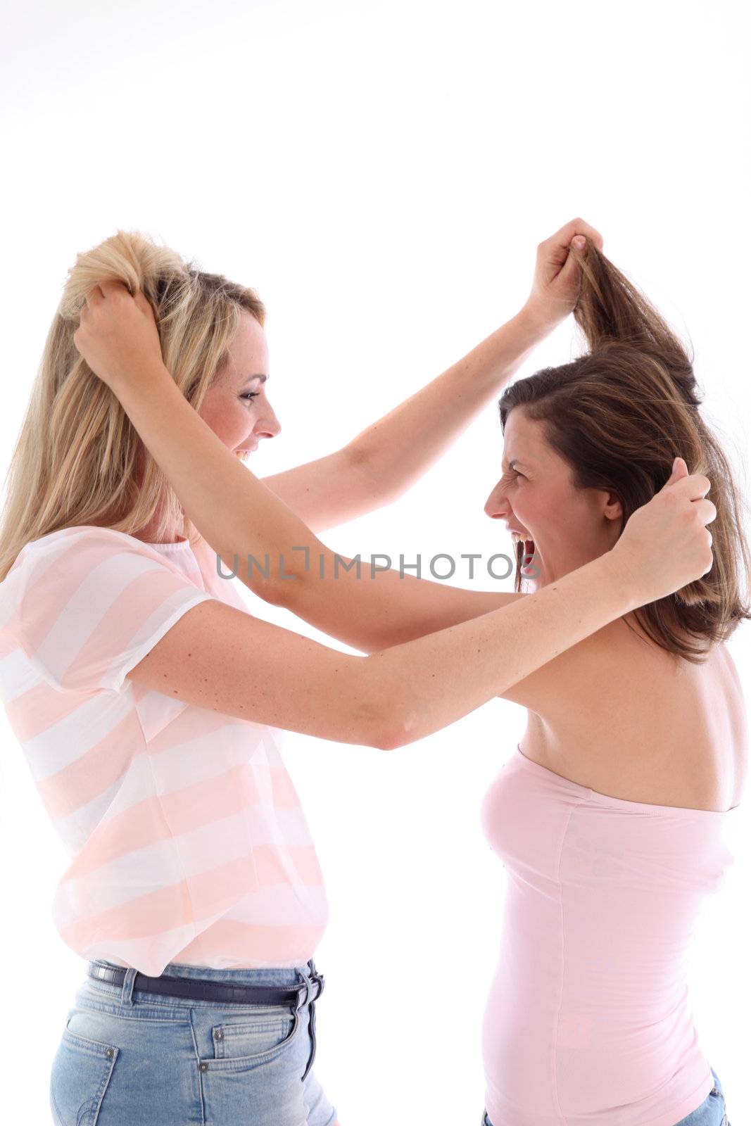 Young women laughing and frolicking together pulling each other's hair while enjoying a bit of fun 