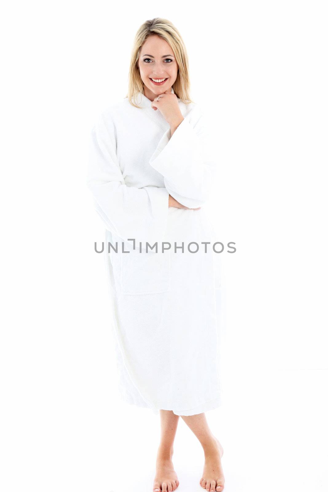 Attractive smiling woman standing barefoot in a white bath robe isolated on a white background Attractive smilinf woman standing barefoot in a white bath robe isolated on a white background