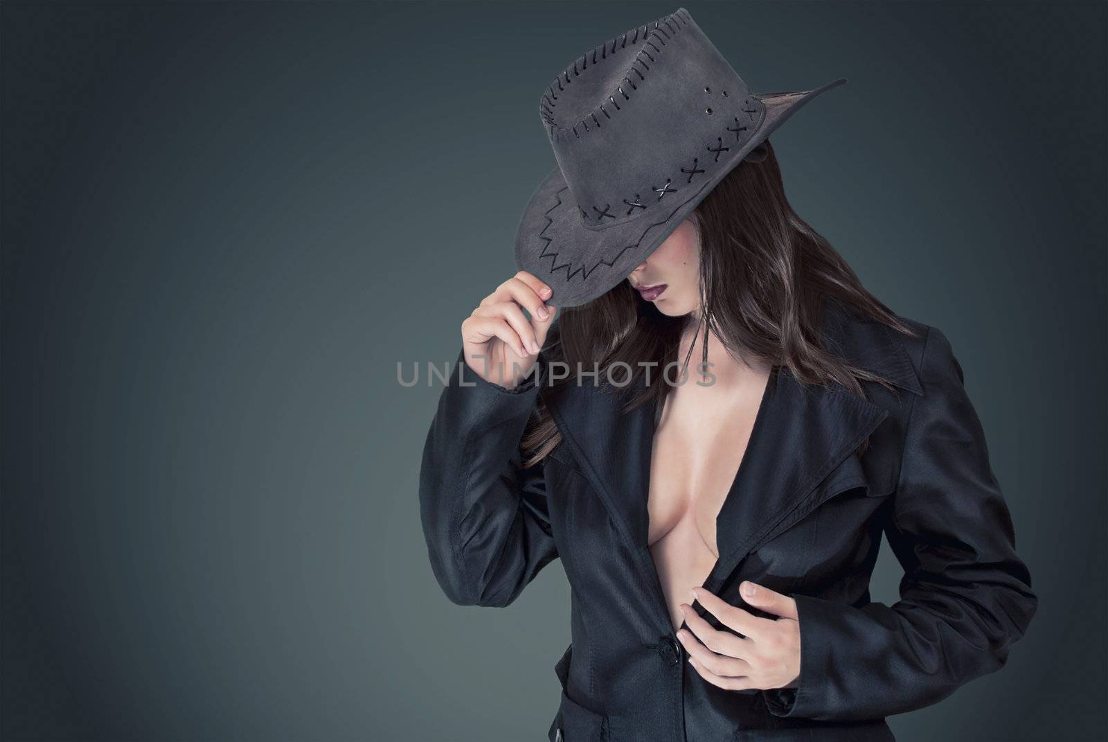 Sexy woman in a cowboy hat in a stylish coat and beautiful breasts.