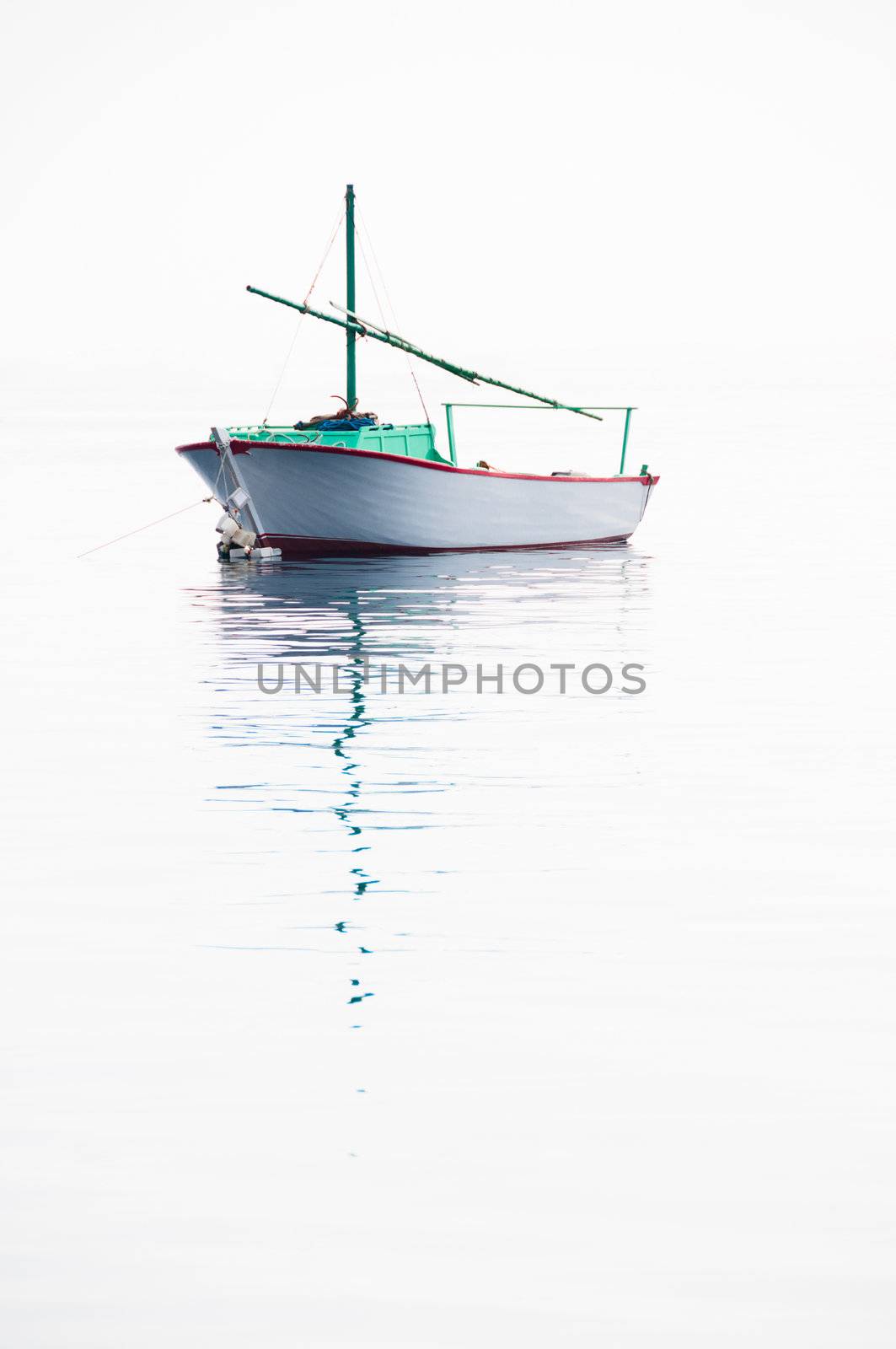 Lonely small fishing boat on very calm sea with smooth surface flowing together with sky