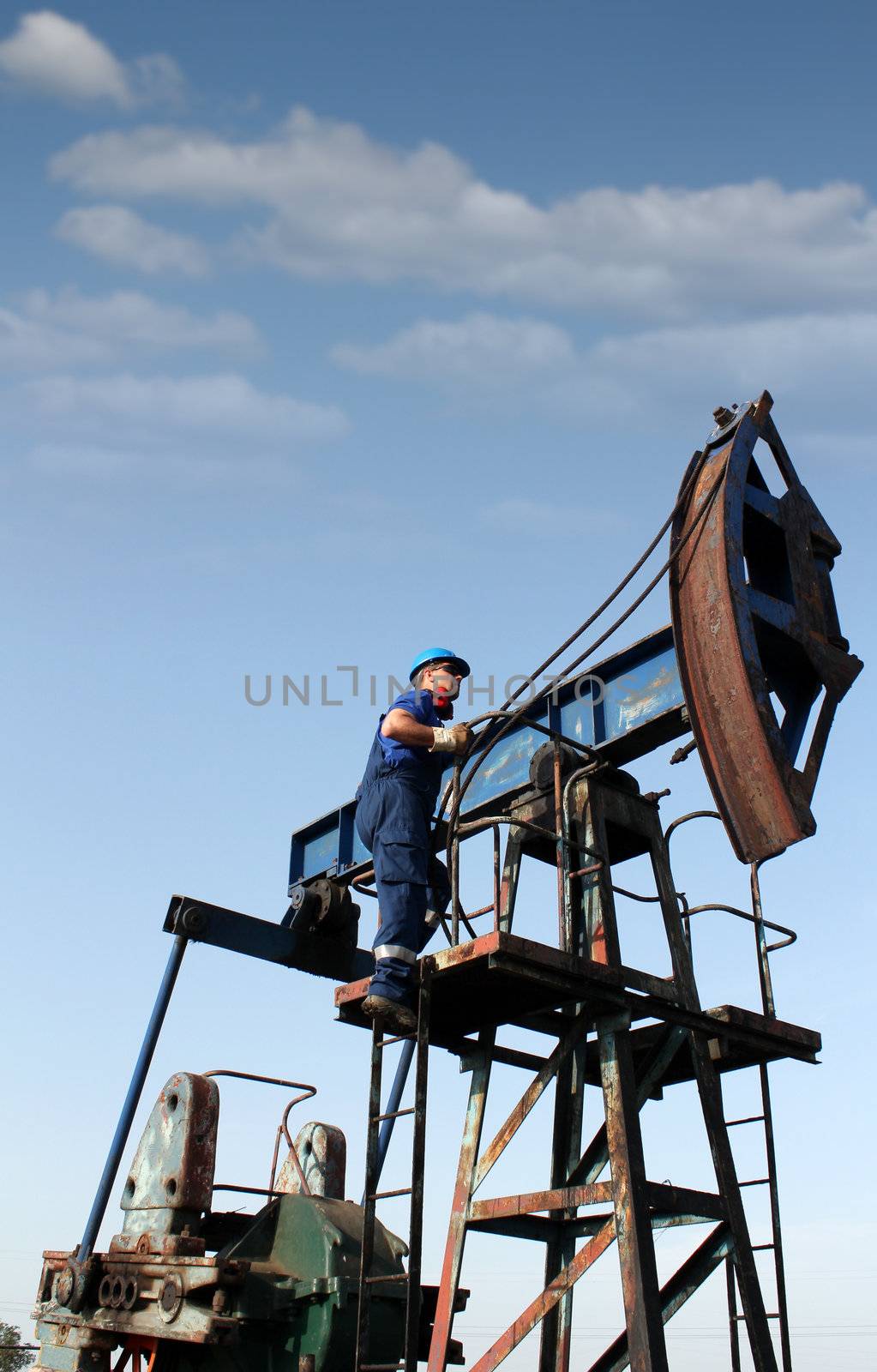 oil worker climbs up to the pump jack by goce