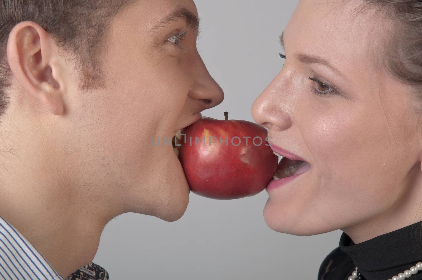 girl and young man bite together red apple