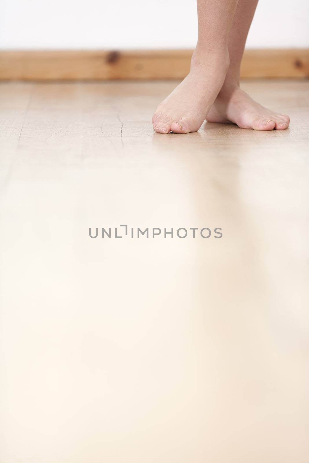 Womans legs on wooden floor against a white wall back drop.