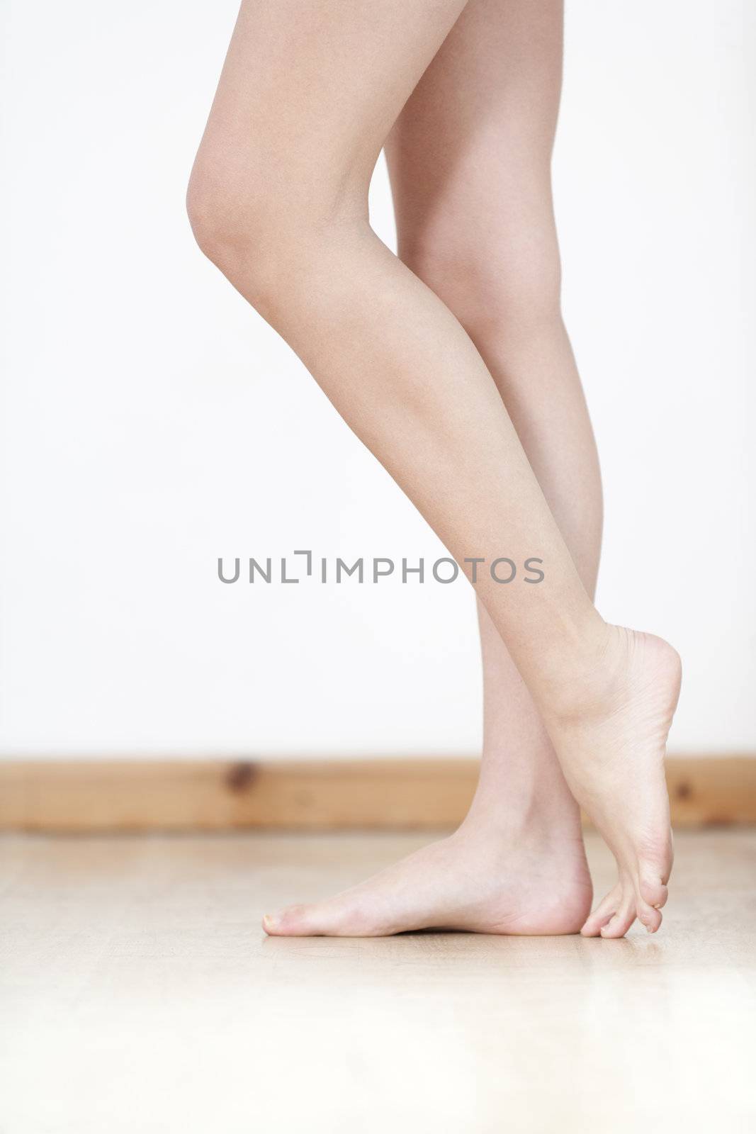 Womans legs on wooden floor against a white wall back drop.