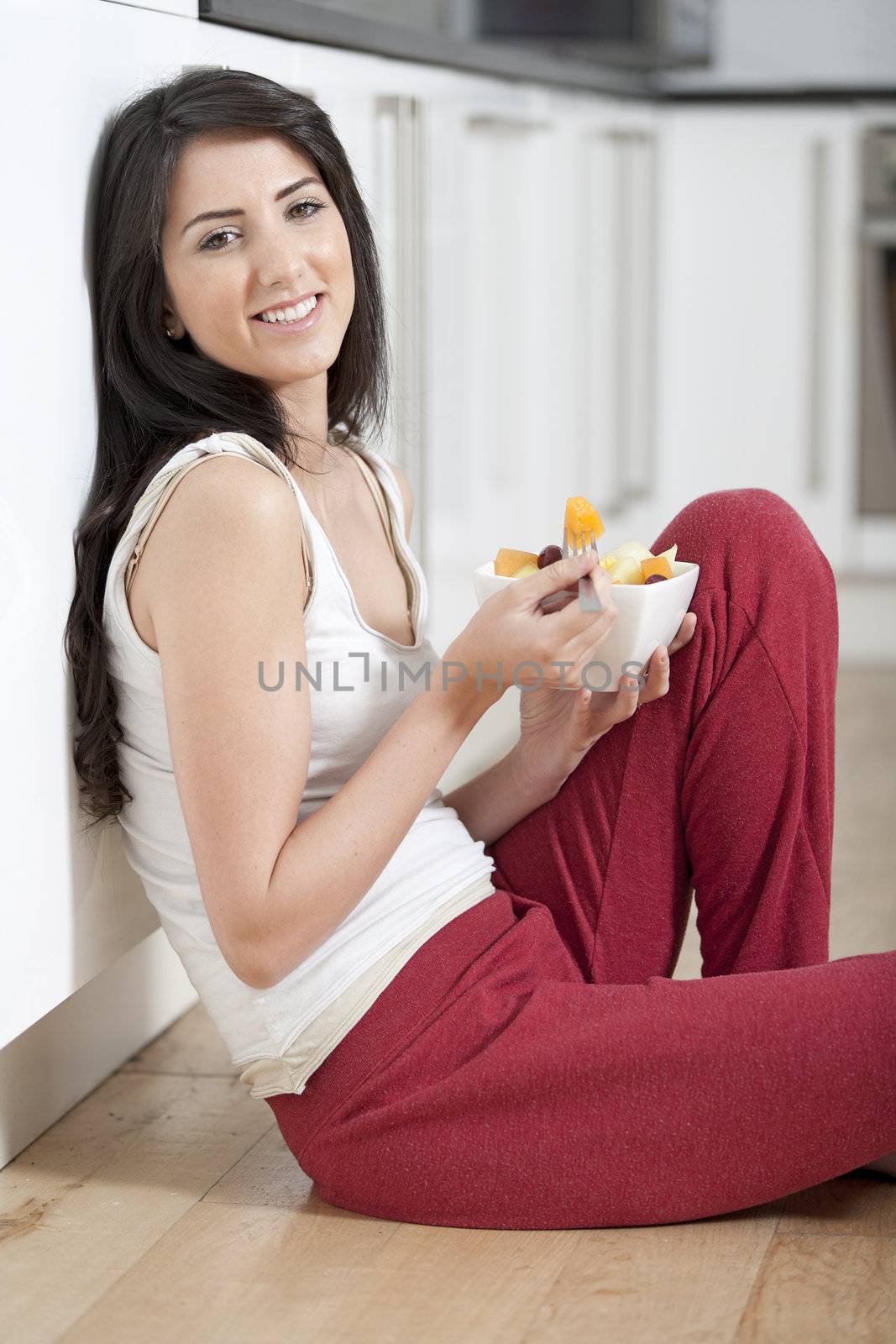 Young woman enjoying a bowl of fresh fruit in her kitchen