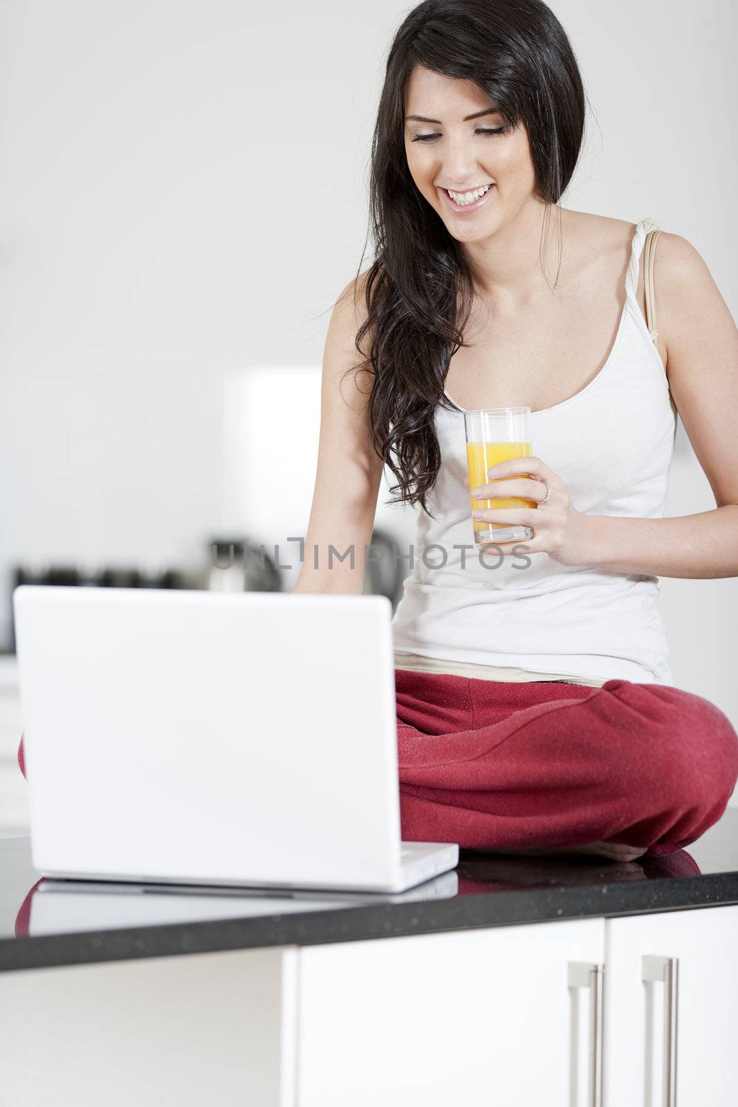 Young woman sat in kitchen on laptop