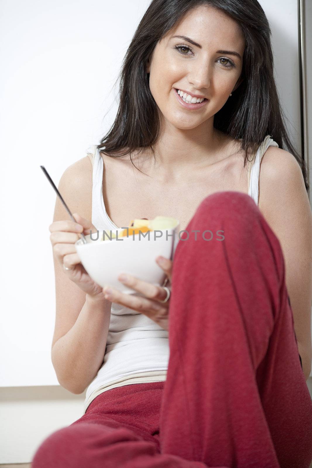 Young woman enjoying a bowl of fresh fruit in her kitchen