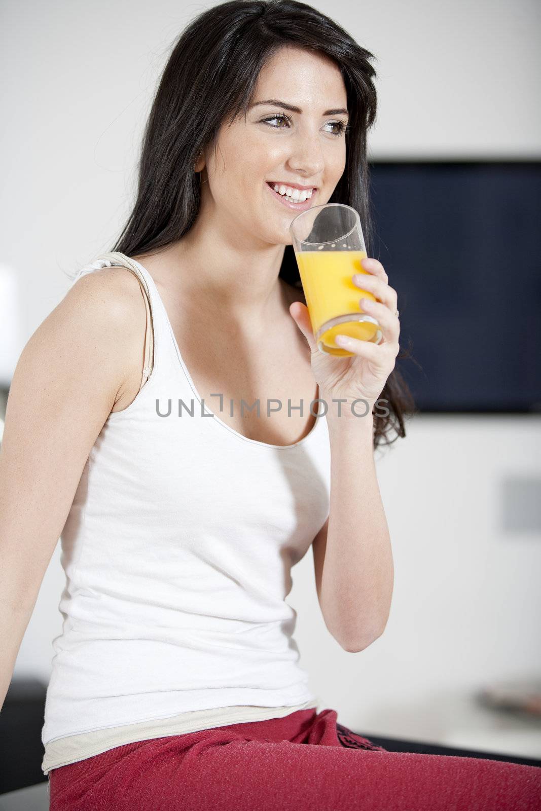 Young woman sitting on counter drinking orange juice