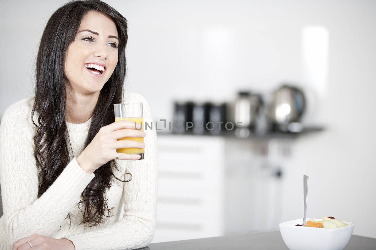 Young woman in kitchen enjoying some orange juice and fresh fruit