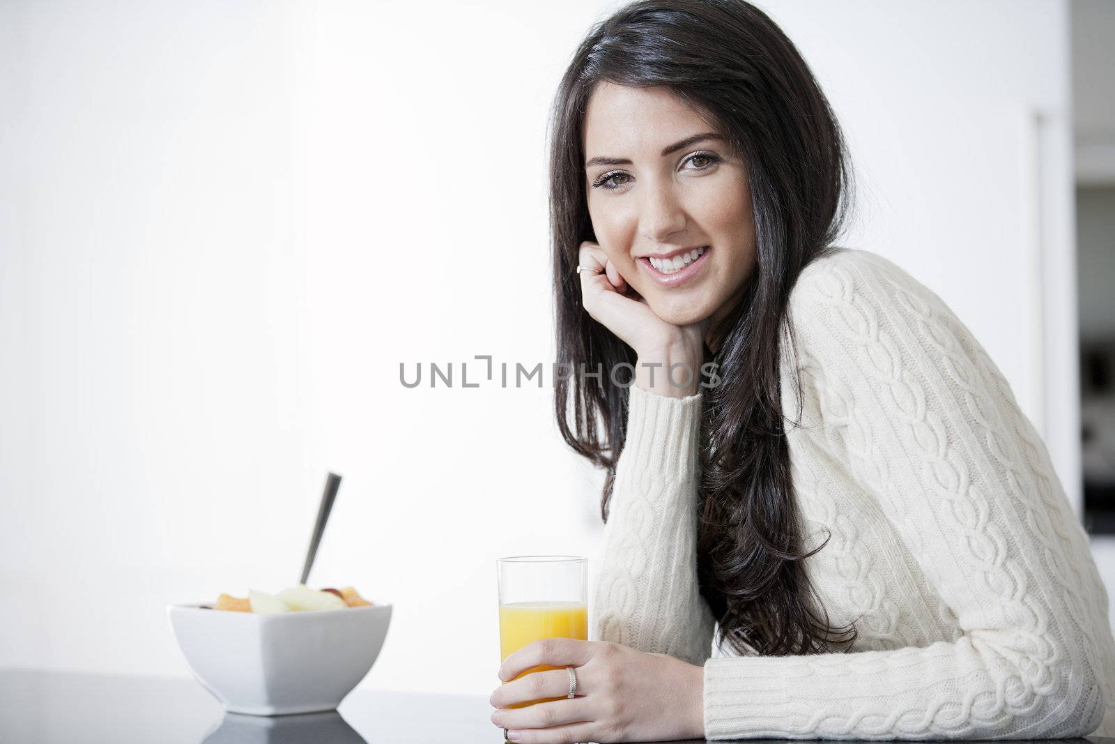 Young woman in kitchen enjoying some orange juice and fresh fruit