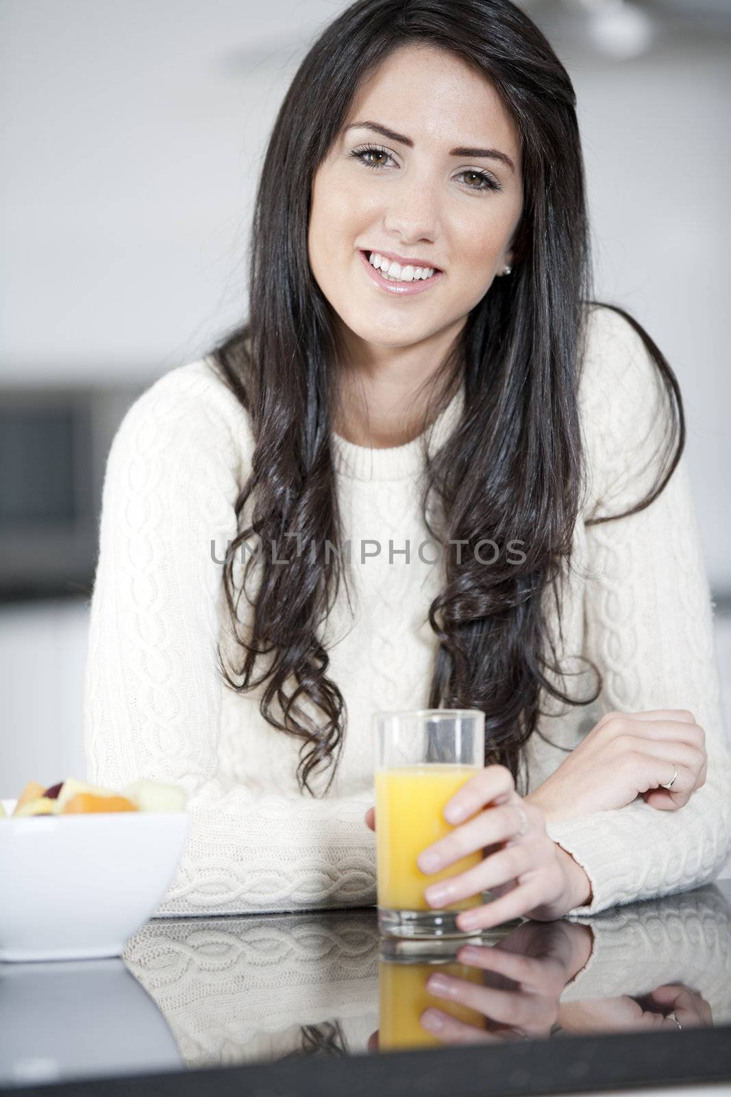 Young woman enyoying a bowl of fresh fruit in her kitchen