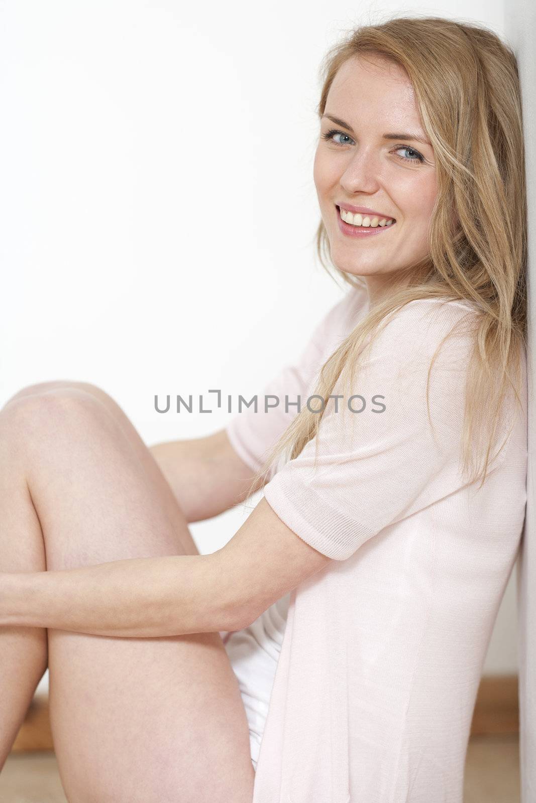 Young woman at home in underwear and pink shirt smiling