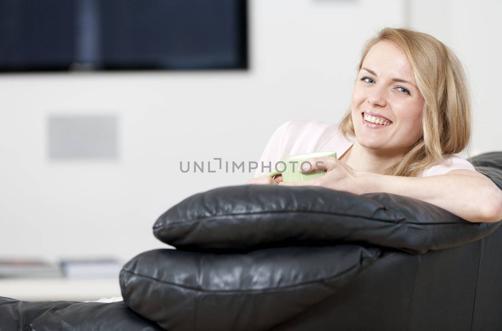 Young woman enjoying a hot drink at home on the sofa