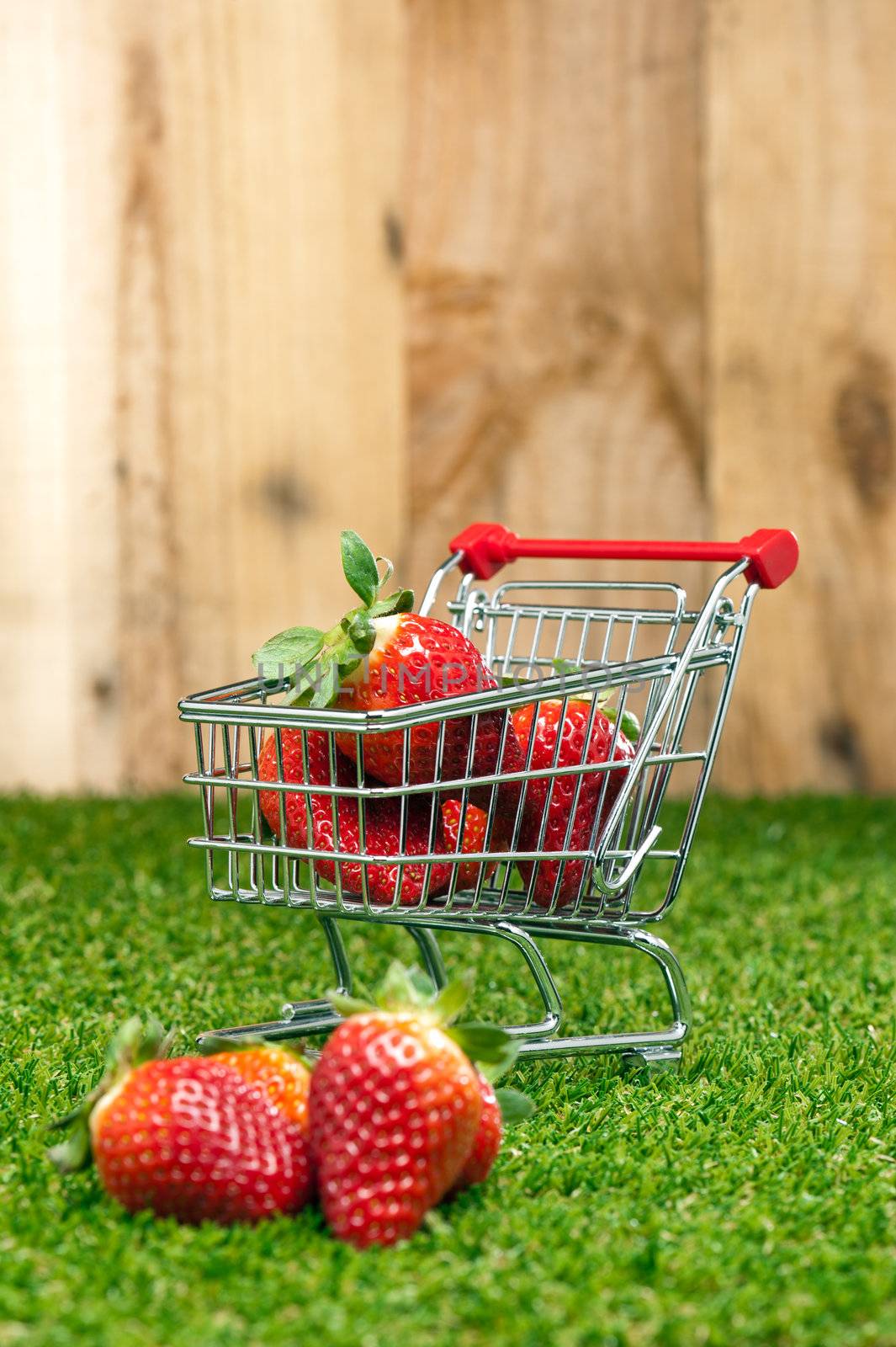 Strawberries in a shopping cart in front of a timber wall