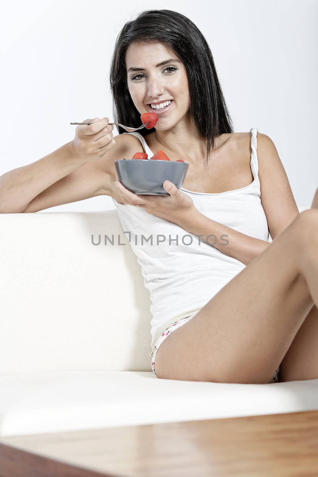 Beautiful young woman enjoying fresh fruit for breakfast at home