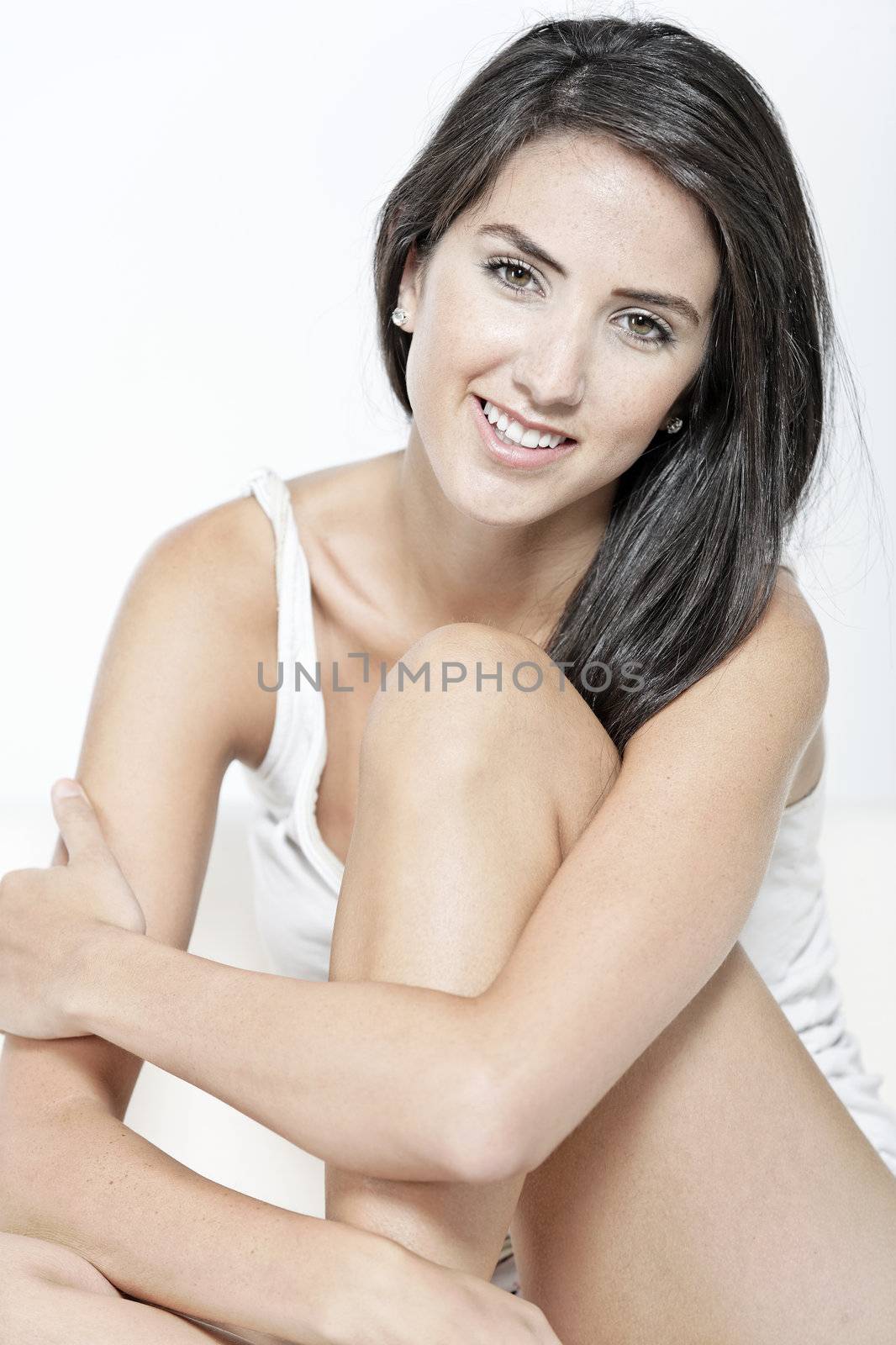 Beautiful sexy woman in white vest top sitting on a white sofa relaxing