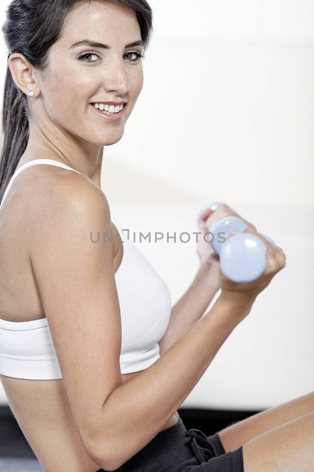 Beautiful young woman training with weights at home