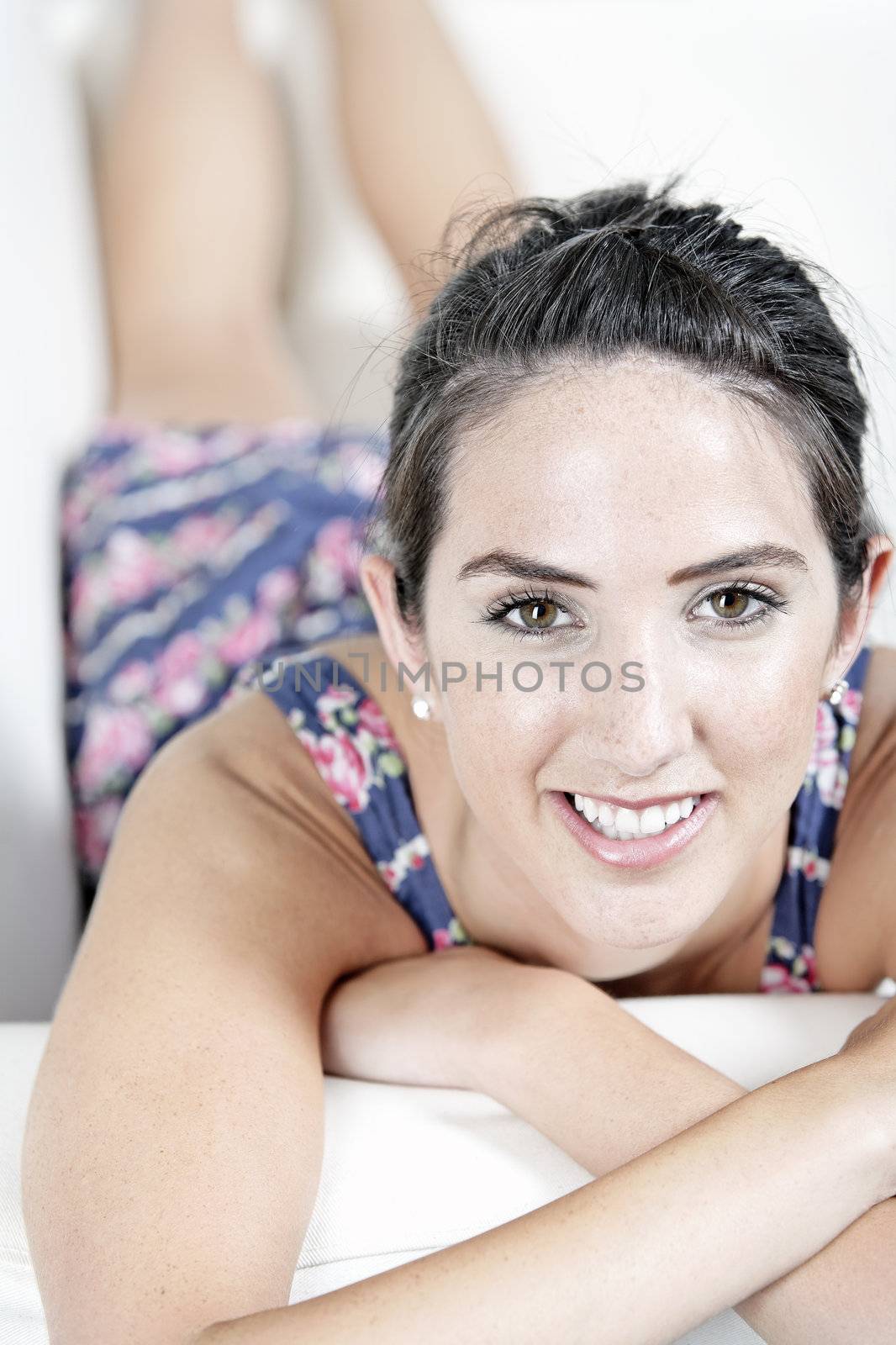 Beautiful young woman wearing a blue summer dress resting on her sofa at home