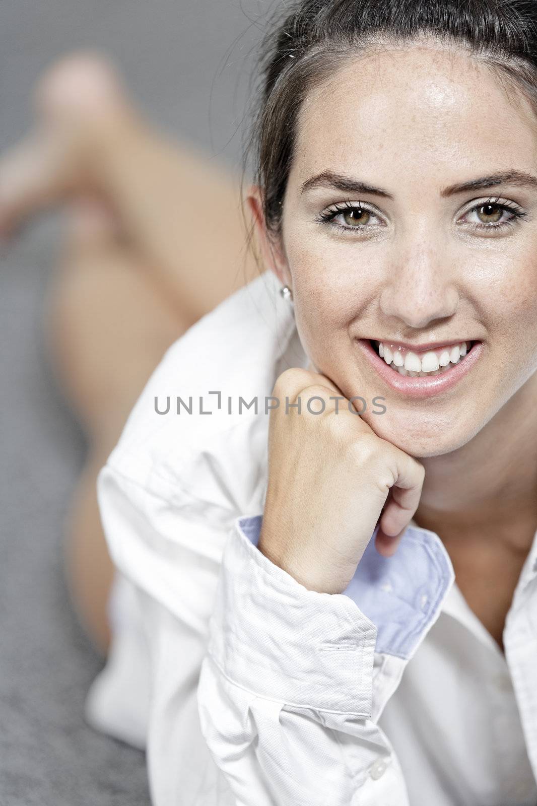 Beautiful young woman in a white shirt lying on her living room floor