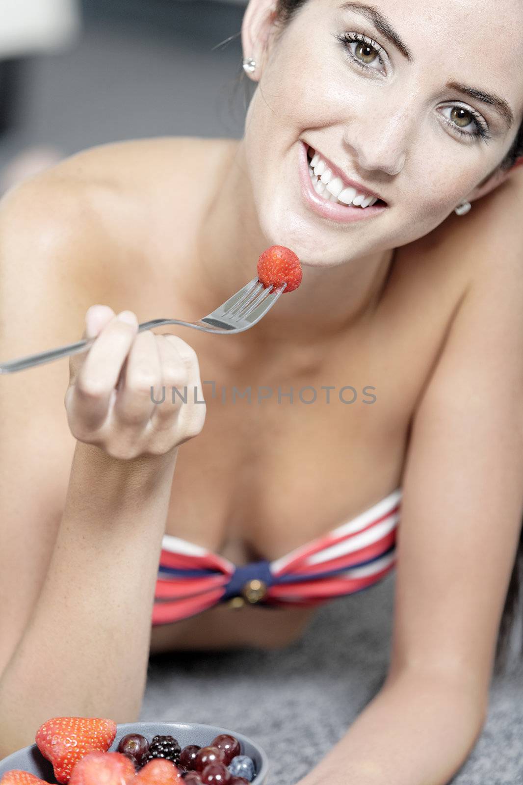 Beautiful young woman enjoying fresh fruit for breakfast in a red bikini
