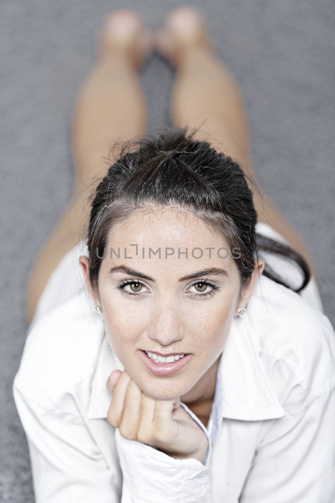 Beautiful young woman in a white shirt lying on her living room floor