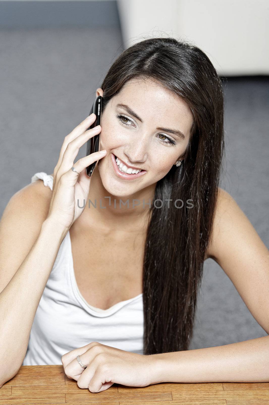 Beautiful young woman talking on her mobile phone at home