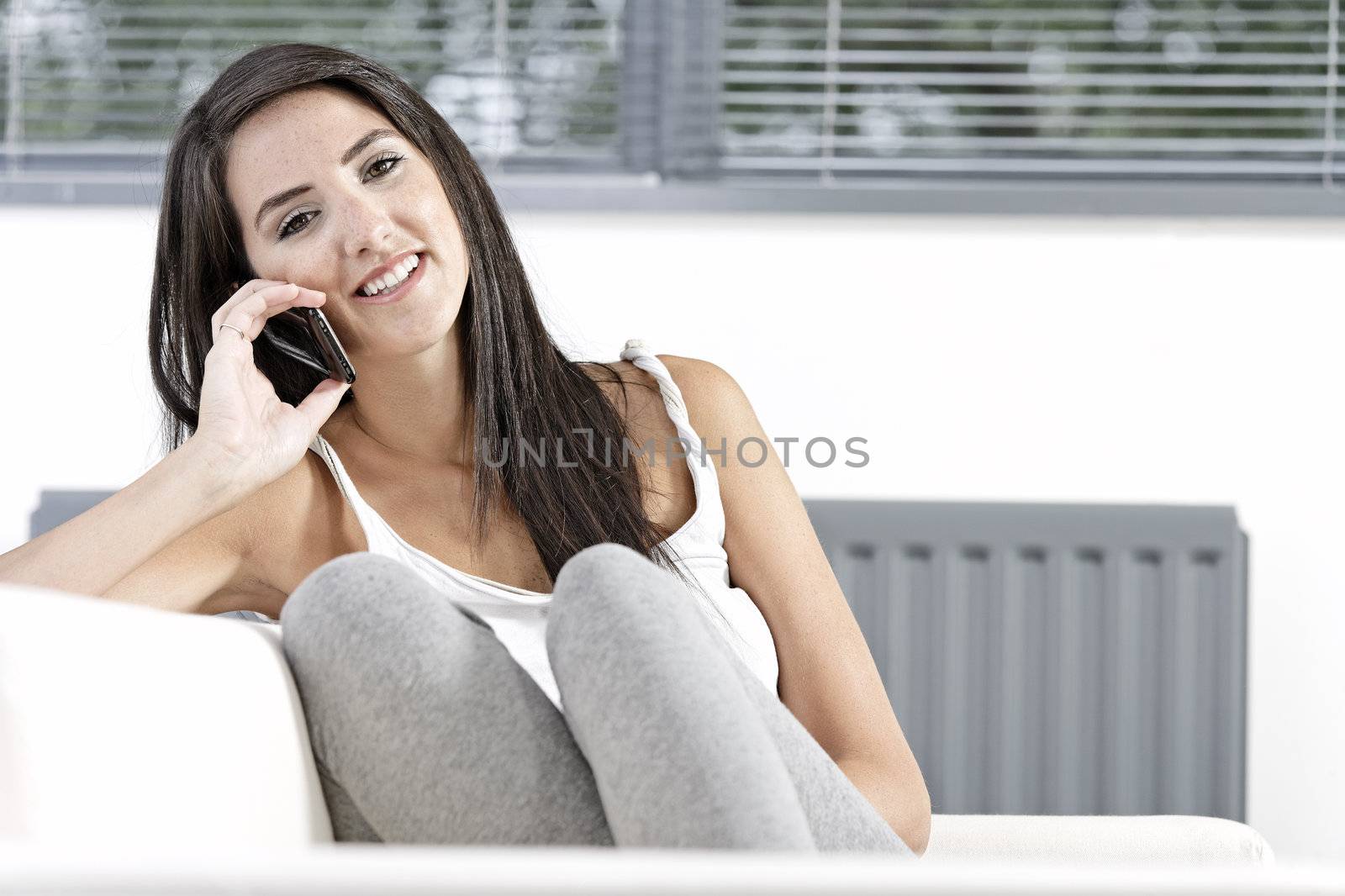 Beautiful young woman talking on her mobile phone at home